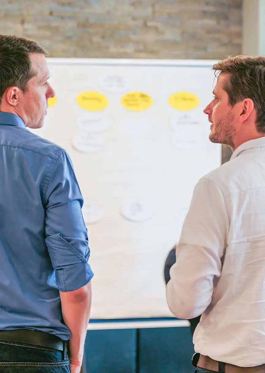 Male employees in conversation in front of a white board